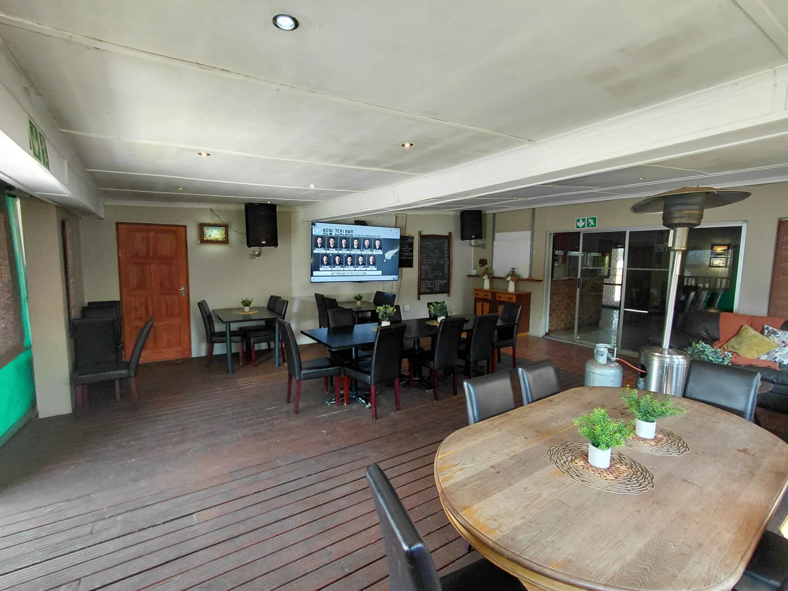 Covered restaurant deck with dining tables and big-screen sports