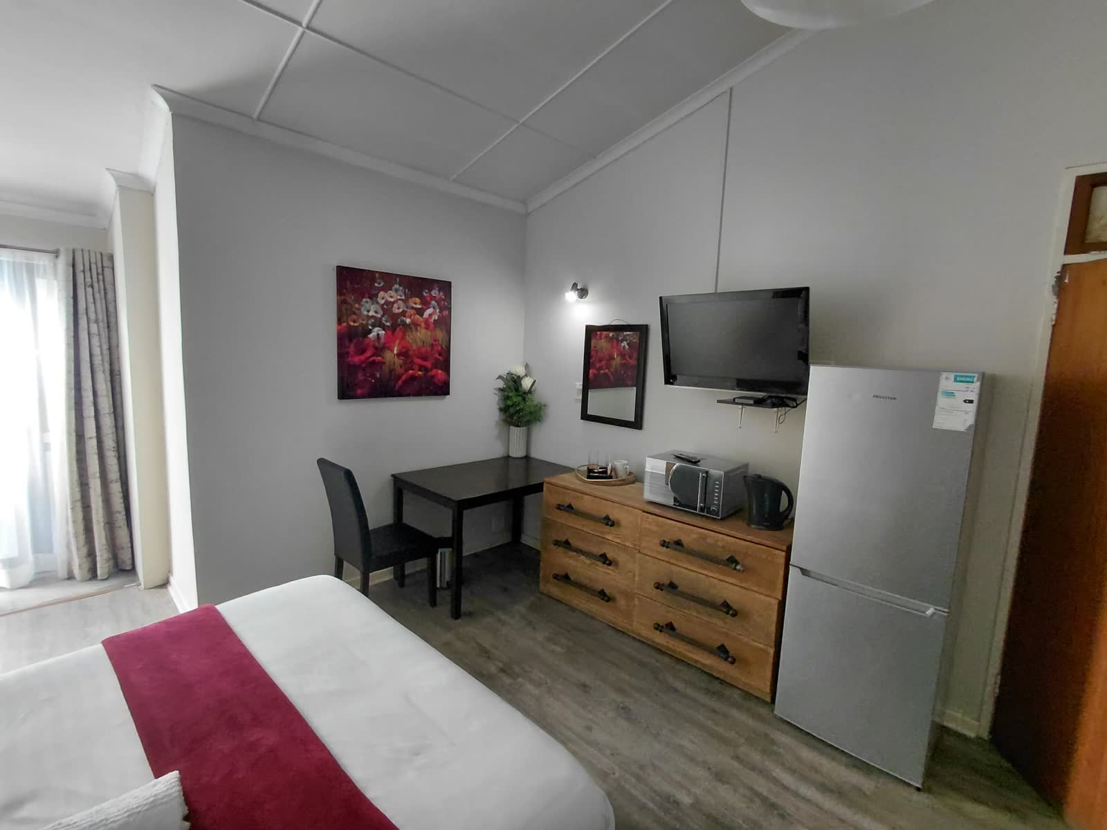 Guest room with desk, mounted TV, microwave, kettle and fridge