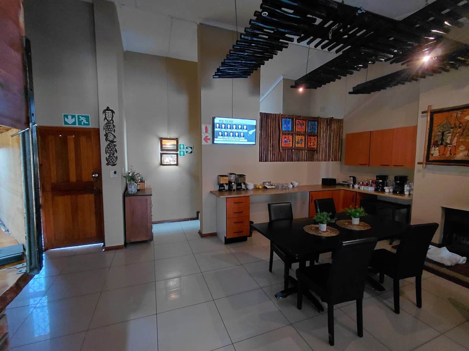 Indoor breakfast room with dining tables, buffet counter and African artwork