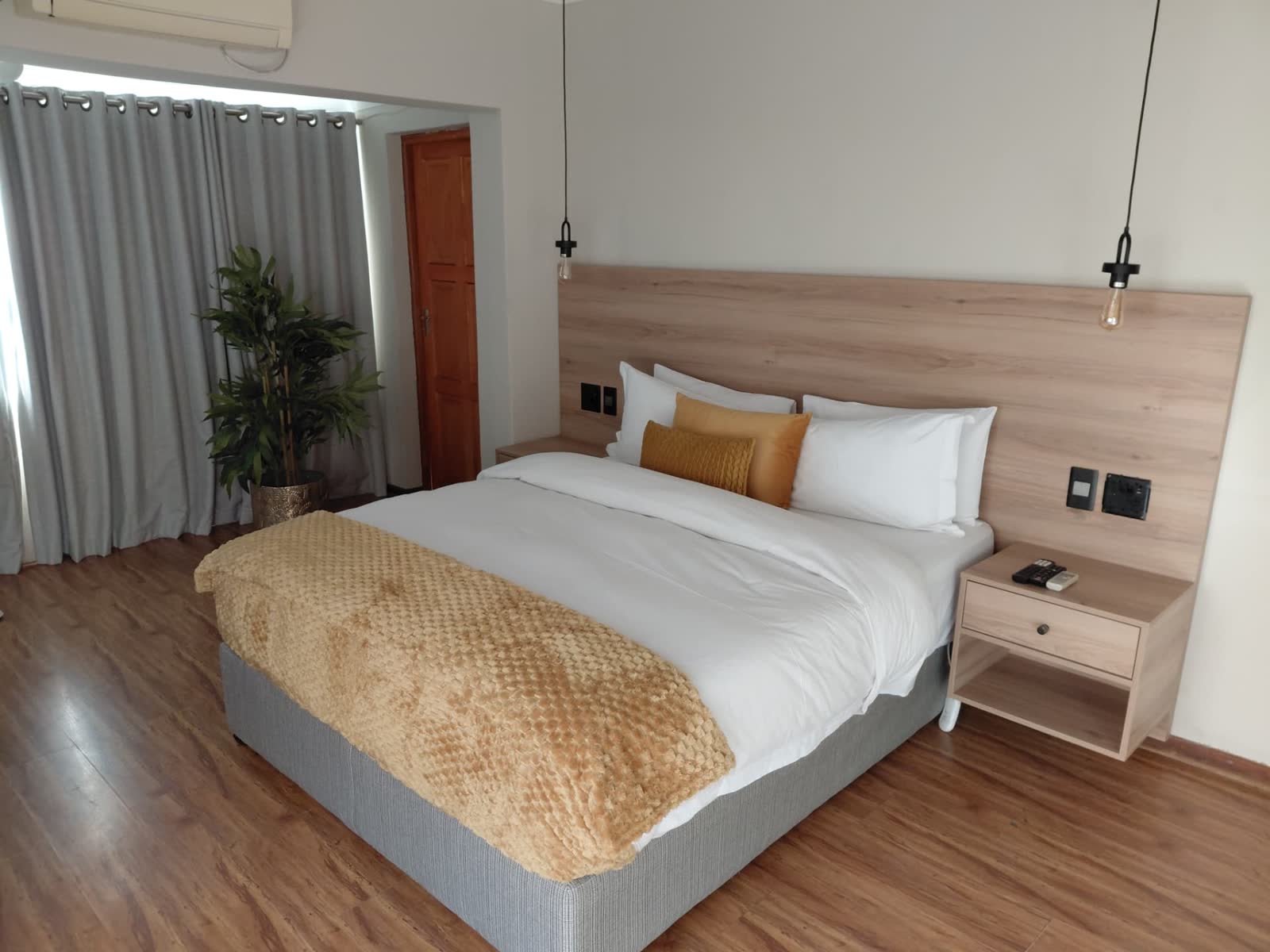 King bed with timber headboard and pendant lighting