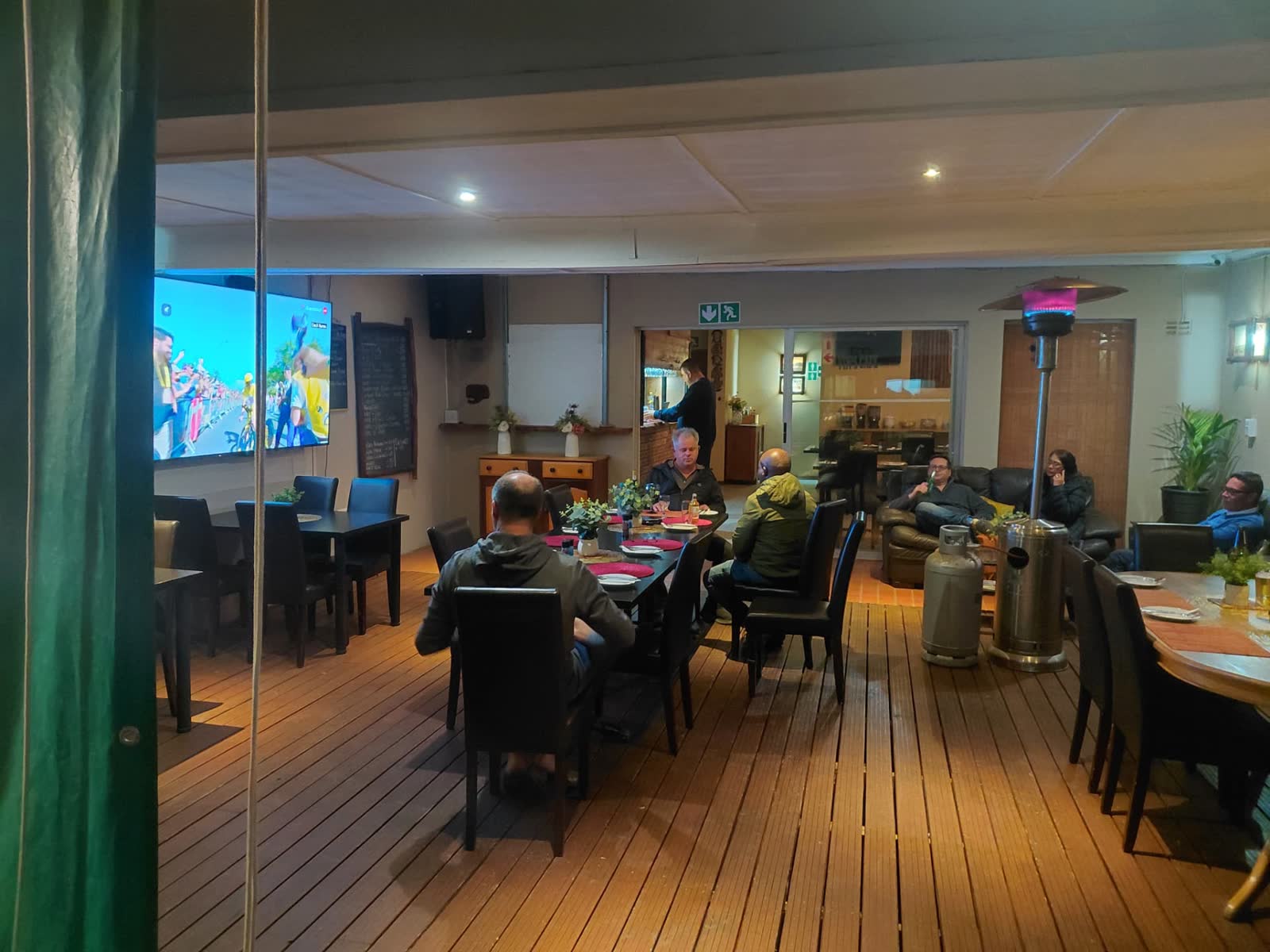 Guests dining on the covered deck with big-screen sports