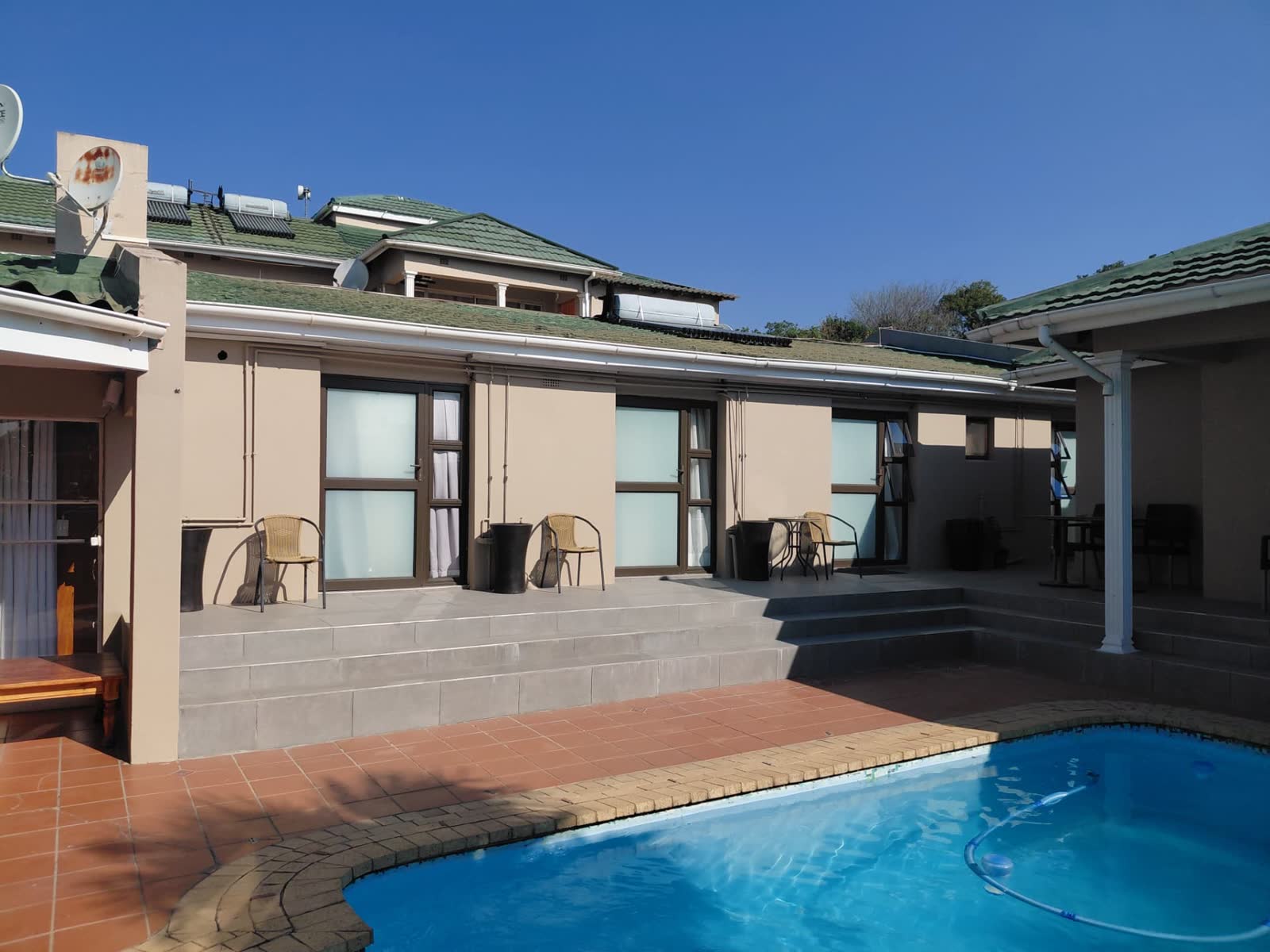 Guest rooms opening onto the pool terrace with outdoor seating