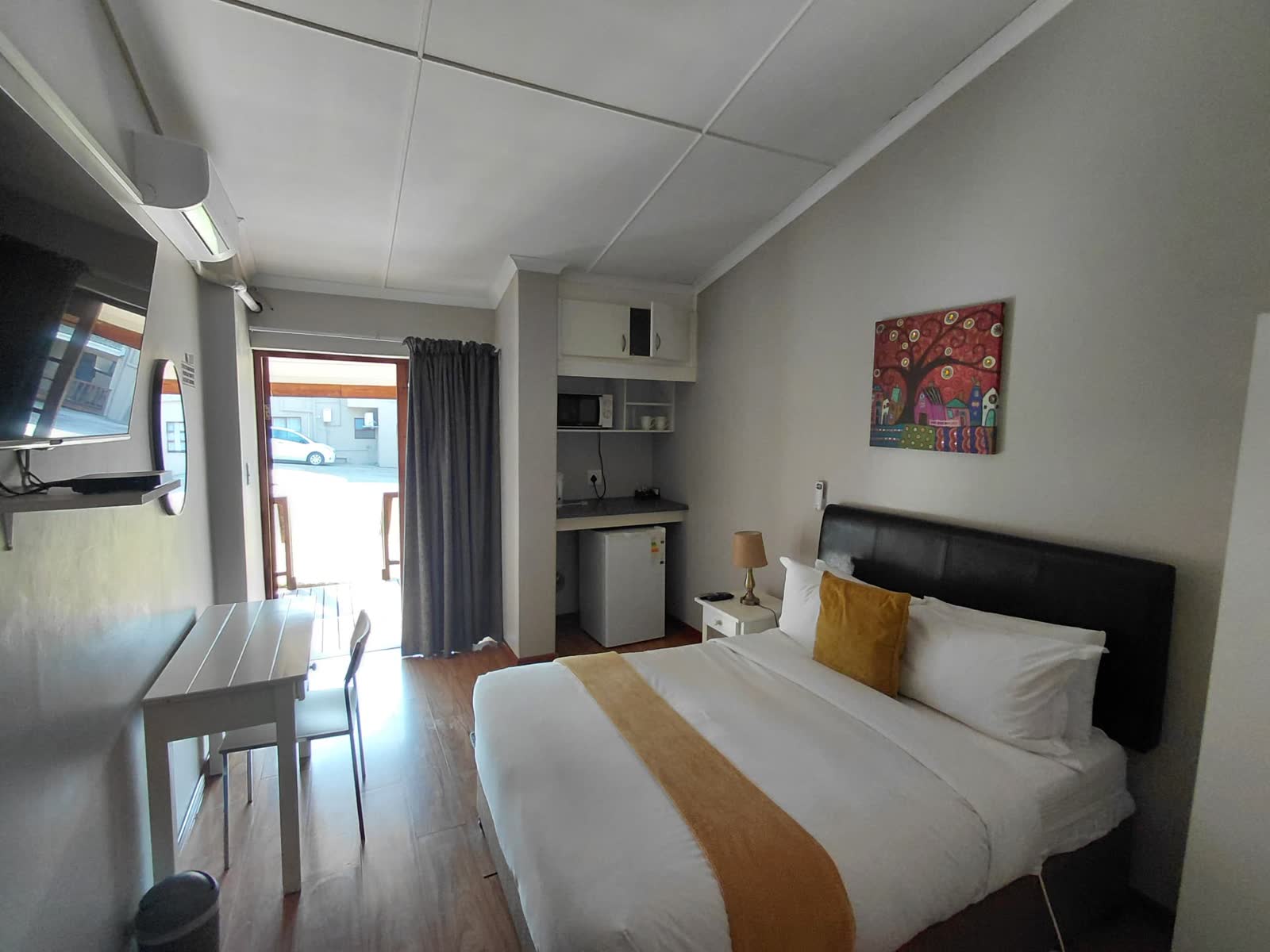 Bright double guest room with gold accents, desk and kitchenette