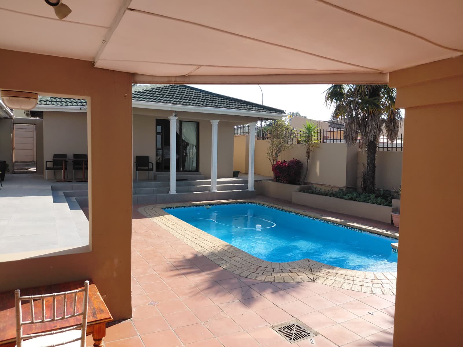 Swimming pool and patio seen from the shaded pool deck